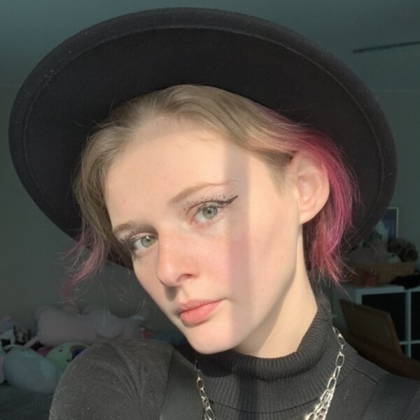 GIRL WITH SHORT HAIR, ENDS DYED PINK, IN A BLACK FEDORA LIKE HAT
